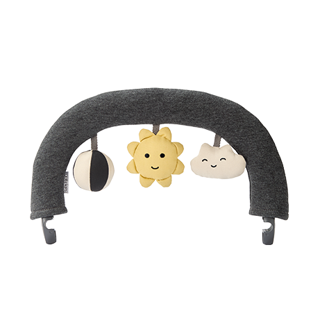 A gray baby bouncer toy arch with hanging plush toys: a black and white circle, a smiling yellow sun, and a happy white cloud.